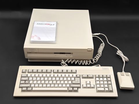 Amiga 3000 desktop case with an AmigaOS 3.2 disc box on top, with its Amiga keyboard and two-button mouse laid out in front