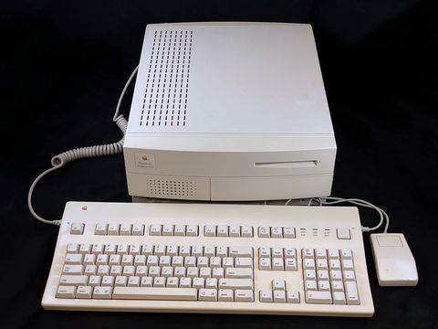 Beige Centris 650 desktop case shown at a front three-quarter angle with its extended keyboard and one-button mouse laid out in front, coiled cable trailing off to the left