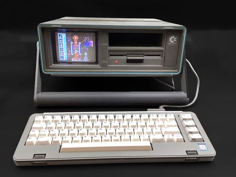 Commodore SX-64 portable with its detached keyboard in front, screen showing a game, and the built-in 5.25 inch floppy drive
