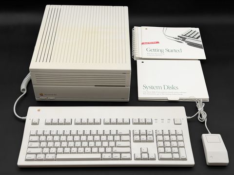 Macintosh IIci desktop case from the front with an Apple Extended keyboard, a one-button ADB mouse, and the Getting Started and System Disks manuals leaning beside it