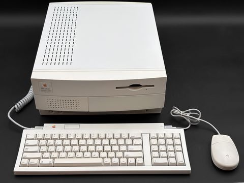 Macintosh Quadra 650 desktop case viewed from the front and above, with its coiled cable to an Apple Keyboard II and a round ADB mouse laid out in front, fully in frame (no monitor)