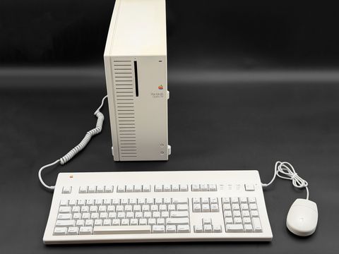 Macintosh Quadra 700 tower standing upright behind an Apple Extended Keyboard II and a round-button ADB mouse, coiled cable running from the tower to the keyboard